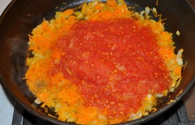 Разогрев сковороду на среднем огне,  пассеруем  на масле нашинкованную луковицу, помешивая, через 5-6 минут добавляем тонко натертую морковь. А еще через 3 минуты – помидоры. Тушим 3-5 минут, приправляем солью и перцем по вкусу, майораном и базиликом. 