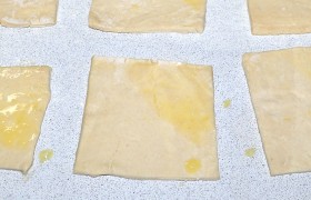 Размороженное тесто нарезаем на квадраты. Обычно получается 12 штук. Если шпроты попались крупные – слегка раскатываем тесто. Один угол смазываем взболтанным яйцом.
