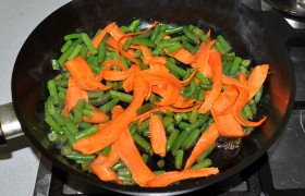 Накрываем крышкой обжаренное мясо, переложенное в тарелку. А в сковороду высыпаем фасоль, через минуту – морковь. Жарим, так же перемешивая, примерно 2 минуты.