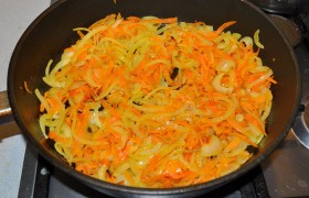 Для заправки солянки разогреваем сковороду с маслом, выкладываем мелко шинкованную луковицу, морковь, натертую на крупной терке, пассеруем на среднем огне 7-9 минут. 
