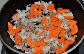 К бекону (или маслу) добавляем мелко порубленный лук и морковь, которую тоже можно натереть. Обжариваем на достаточно сильном огне 2-3 минуты.