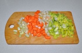 Для заправки этого супа мы не тратим время на мелкую нарезку: нарезаем средним кубиком сельдерей, лук, на 4 части делим вдоль, рубим поперек и морковь, и белую часть лука-порея.  Раздавливаем  плоской стороной ножа чеснок. 