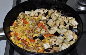Нарезанный баклажан загружаем в сковороду вместе с кукурузой. Все так же обжариваем, перемешивая, 4-5 минут.