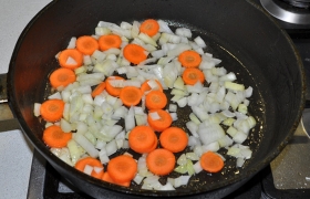 В сковороду засыпаем лук и морковь, не меняя сильного огня и так же помешивая, обжариваем 3-4 минуты.  