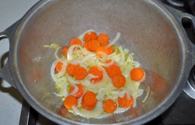 На другую, со средним огнем, помещаем латку или кастрюлю с толстым дном, пригодную для тушения. В ней разогреваем масло и   пассеруем  морковь с луком 6-7 минут.