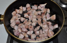 Для жарки масло, влитое в большую сковороду, сначала  перекаливаем  на самом большом огне. Выкладываем кусочки свинины, жарим примерно 3 минуты, перемешивая, пока мясо светлеет и начинает обзаводиться корочками. 