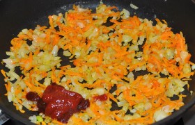 Включаем на 200° духовку, а на конфорку со средним огнем ставим сковороду для соуса. В разогретом масле 5-6 минут  пассеруем  средним кубиком нашинкованный лук, добавляем тертую морковь, через 4-5 минут посыпаем мукой, помешиваем 2 минуты, кладем и размешиваем томатную пасту. Вливаем сливки, воду, даем прокипеть минуту – и выключаем.