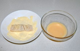 Взбиваем яйцо, добавив ст. ложку молока и щепотку соли. А в тарелку насыпаем кукурузную муку, в которой обваливаем треску. 
