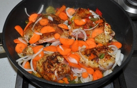 Добавляем нарезанные лук и морковь, переводим огонь на небольшой и оставляем курицу с овощами  тушиться  18-20 минут под крышкой.