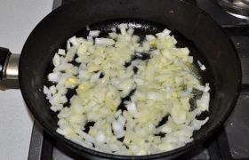 Тем временем ставим разогреваться сковороду на средний огонь. Шинкуем кубиком луковицу. Кладем масло, оно закипело – сыплем лук,  пассеруем  его, помешивая, 5-6 минут.