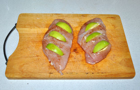 Довольно толстыми дольками нарезаем яблоко и вкладываем в разрезы. При 200° ставим форму с филе в духовку. 
