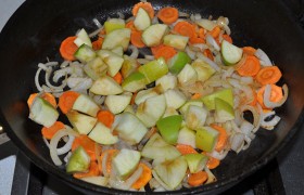 Меняем огонь под сковородой на средний, засыпаем средне нашинкованный лук и нарезанную морковь (можем и натереть ее),  пассеруем , временами помешивая, 5-6 минут. Добавляем нарезанные кубиком яблоки, продолжаем пассеровать еще 5-6 минут. Выкладываем зажарку к мясу (не обязательно казан, подойдет и толстостенная кастрюля). 