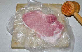 Чтобы сохранить текстуру мяса и избежать брызг, кладем мясо между слоями пленки (или внутрь пакетика),  отбиваем  с помощью деревянного молотка. Толщина уменьшается до 8-9 мм. Полоска сала стягивает мясо? Делаем 1-2 рассечки на ней.