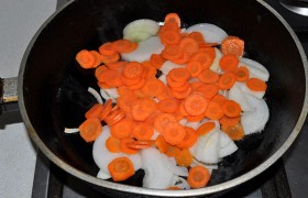 Чистим морковь и лук. Лук шинкуем полукольцами, морковь - тонкими полу - или кружочками. Как следует разогрев немного растительного масла, засыпаем в сковороду лук и морковь, перемешиваем, переводим на средний огонь и не спеша, 10-12 минут,  доводим лук до слегка золотистого цвета.