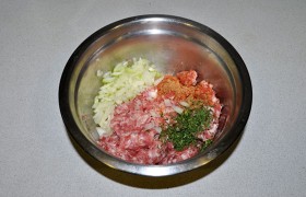 В перемолотое мясо добавляем зелень, соль и перец, приправу, мелко порубленный лук, вымешиваем.