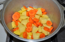 Чистим и достаточно крупно нарезаем картофель и морковь. Отправляем в посуду для тушения. Приправляем перцем, солью. Мы готовим сегодня без лука, если вам без него никак – добавляйте лук.