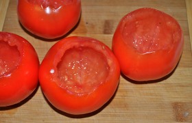 Из вымытых и обсушенных помидоров вырезаем плодоножку, расширяем отверстие, чтобы удобно было положить начинку. Очень большие помидоры просто разрезаем поперек на половинки. Ложечкой аккуратно вынимаем мякоть, оставляя нетронутыми стенки, выливаем сок.