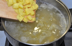 В кастрюлю, где практически сварилась крупа, добавляем нарезанный картофель, немного солим и бросаем горошки перца, лавровый лист.