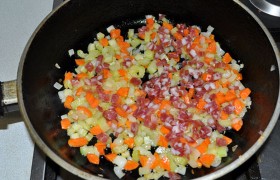 На разогретом масле минут 7-9 слегка обжариваем нашинкованные мелким кубиком морковь, сельдерей и лук, кладем колбасу. 