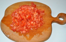 Подготавливаем помидоры – счищаем кожицу и рубим на мелкие кубики, тоже отправляем в сковороду, сыплем свежую или сушеную зелень, 