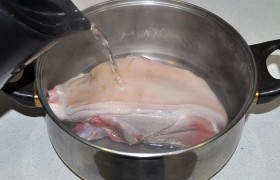 Свиной окорок кладем кожей вверх в большую миску или кастрюлю и обливаем 1,5 - 2 литрами кипящей воды. Сразу же сливаем воду из емкости, а свинину оставляем на 10 минут.