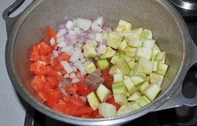 Все ингредиенты нарезаем тем же кубиком. Но томаты предварительно купаем в кипятке, чтобы избавиться от кожицы. К готовому мясу добавляем лук и томаты, сладкий перец, кабачки, томатную пасту и сахар. Приправляем перцем и солью.