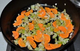 Мелко рубим луковицу, сельдерей и морковь, переводим огонь под сковородой на средний. Загружаем овощи,  пассеруем  при периодическом помешивании 7-8 минут. 