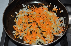 Параллельно готовим заправку супа: ставим сковороду с растительным маслом разогреться на среднем огне, шинкуем лук и  пассеруем  его 5-7 минут, периодически помешиваем. Засыпаем тертую морковь, продолжаем пассеровать 4-5 минут.