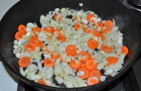 На сковороду, поменяв огонь под ней на средний, засыпаем нашинкованные морковь, лук, сельдерей, пассеруем при периодическом помешивании 9-10 минут, до прозрачности лука.