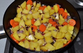 Если надо – добавляем и разогреваем еще масла. Кладем очищенные и нарезанные картофель и морковь, не снижая огня и продолжая помешивать, обжариваем 4-5 минут. 