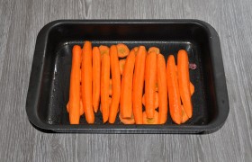 Несколько морковок разрезаем пополам вдоль и плотно выкладываем в промазанную маслом форму,