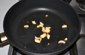 Сковороду раскаляем с маслом на сильном огне. Нарезанный чеснок кладем в сковороду и 40-50 секунд обжариваем, подрумяниваем, помешивая. Убираем чеснок.