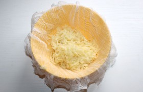 Натираем на средней или крупной терке очищенный картофель тонкими длинными «перышками» в миску с марлей и отжимаем картофельный сок. 