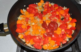 и мы добавляем нарезанные помидоры и томатную пасту, и в это же время включаем конфорку под кастрюлей – пусть закипает.