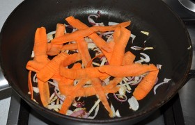 Лук шинкуем половинками колец, тонкими. И нарезаем с моркови – с помощью ножа для овощей – широкие полоски, совсем тонкие, полупрозрачные. На второй сковороде, разогретой с маслом на огне побольше среднего, 4-5 минут обжариваем, помешивая.