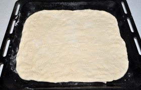 И с помощью того же листа перемещаем тесто на противень, поправляем его форму. Печь можно либо на промазанном маслом противне - или застелить пергаментом и печь на нем. Вилкой делаем по всей поверхности мелкие отверстия, которые уберегут тесто от вздутия.