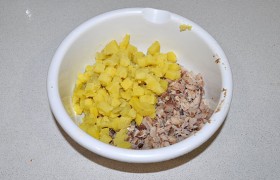 Подоспевший картофель нарезаем кубиком и добавляем в миску с рыбой.