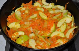 Перекладываем отбивные в тарелку. Ставим огонь чуть выше среднего, засыпаем в сковороду порубленный кубиком лук, через 4-5 минут – крупно тертую морковь и тонкие дольки яблок. Помешивая, обжариваем все вместе 5 минут.