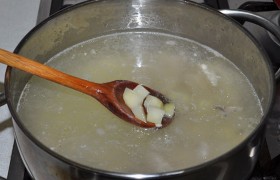 Пока варится каша, на другую конфорку ставим кастрюлю с бульоном, чистим, нарезаем картофель и после закипания кладем в бульон. Добавляем и сушеную или свежую морковку.