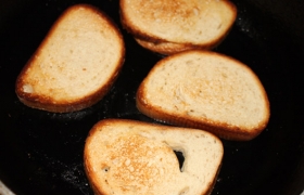В то же время на другой сковороде, побольше, поджариваем кусочки хлеба с небольшим количеством масла до образования поджаристой корочки.