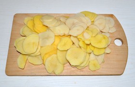 Очищенные картофелины легко превращаем в тонкие  слайсы  (2 мм) с помощью терки для капусты. Ломтики смешиваем с перцем и солью. 
