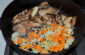 Когда говядина уже почти готова, на второй сковороде разогреваем масло на среднем огне, пассеруем 6-7 минут лук, нашинкованный полукольцами, и морковь. Добавляем нарезанные грибы, тушим 3-4 минуты – или немного дольше, если грибы замороженные и в них много жидкости. 