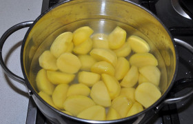 Очищенные картофелины делим пополам, более крупные нарезаем дольками.  Ждем закипания и варим 3-4 минуты. Сливаем воду.