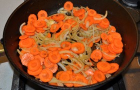 В той же сковороде – но уже на среднем огне – 10-12 минут пассеруем нашинкованный полукольцами лук и кружки моркови.
