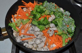 Как только все кусочки посветлели - добавляем морковь, брокколи и зеленый горошек. Все время помешивая лопаткой, обжариваем все вместе 2,5-3 минутки. Не доводим до мягкости – овощи в этом блюде нужны похрустывающие. Солим по вкусу, перчим.