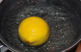 Сначала нам надо сварить лимон, что мы и делаем, положив его в воду и оставив слабо кипеть под крышкой 9-10 минут. Готовый лимон, который стал похож на резиновый желтый мячик, обдаем холодной водой.
