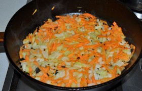 Снижаем огонь под сковородой до среднего, кладем лук, нашинкованный средним кубиком, тертую морковь и порубленный сельдерей.  Пассеруем , помешивая, 7-8 минут. 