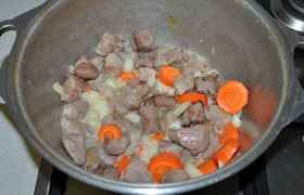 Перекладываем мясо в посуду для тушения, посыпаем приправой, наливаем немного, примерно полстакана, воды. Добавляем лук, нашинкованный крупным кубиком, и крупно нарезанные морковки. На слабом огне оставляем мясо тушиться на 20-30 минут, когда оно станет почти мягким.