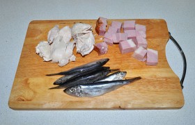 Нарезаем кусочками мясо курицы и ветчину, у кильки отделяем филе без кожи.