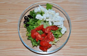 В качестве подготовки – нарезаем помидоры, маслины, мелким кубиком – фету. Аккуратно перемешиваем вместе с зеленым салатом.